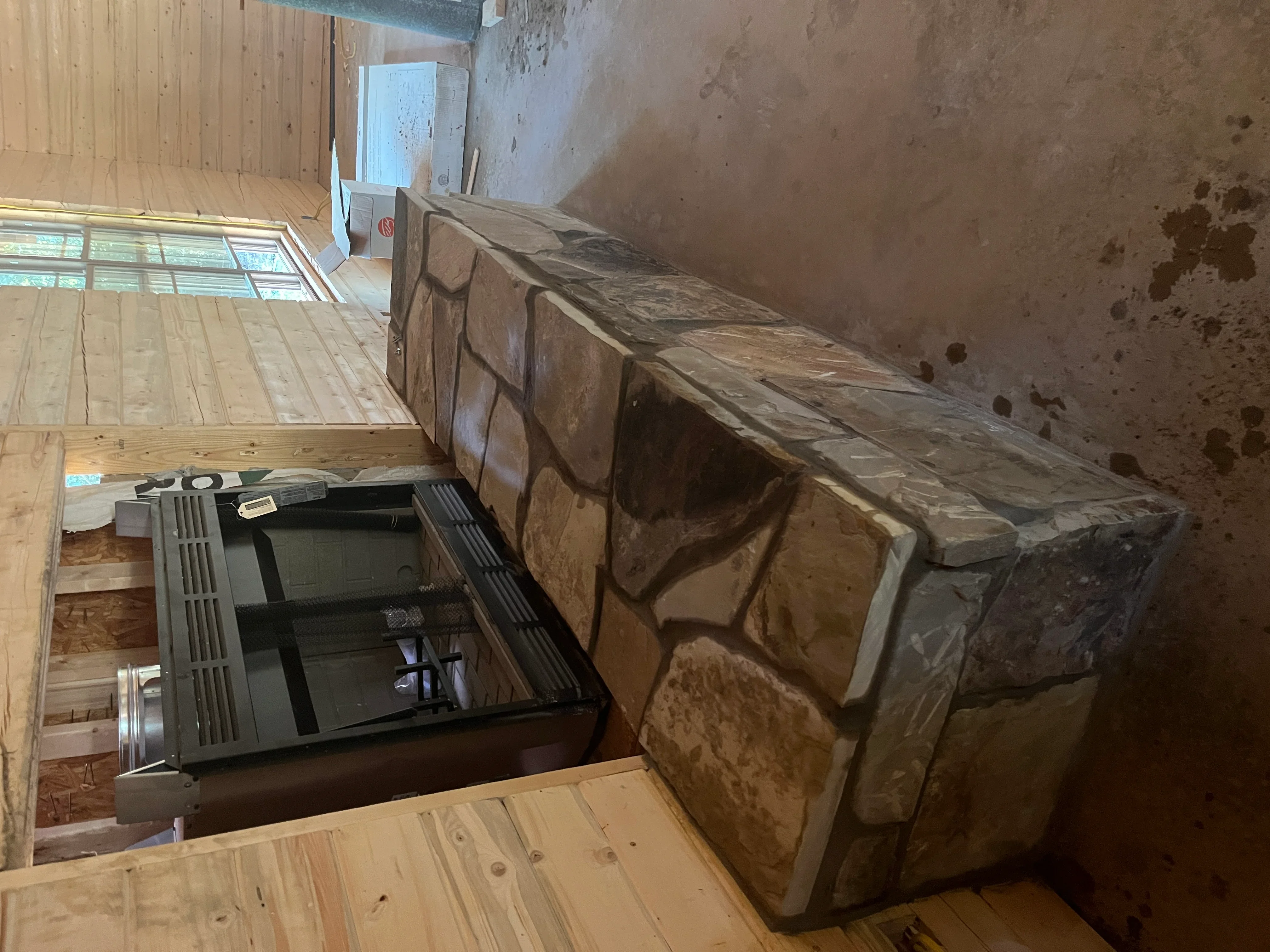 Interior demolition showing exposed wood framing, removed cabinetry, and concrete foundation walls