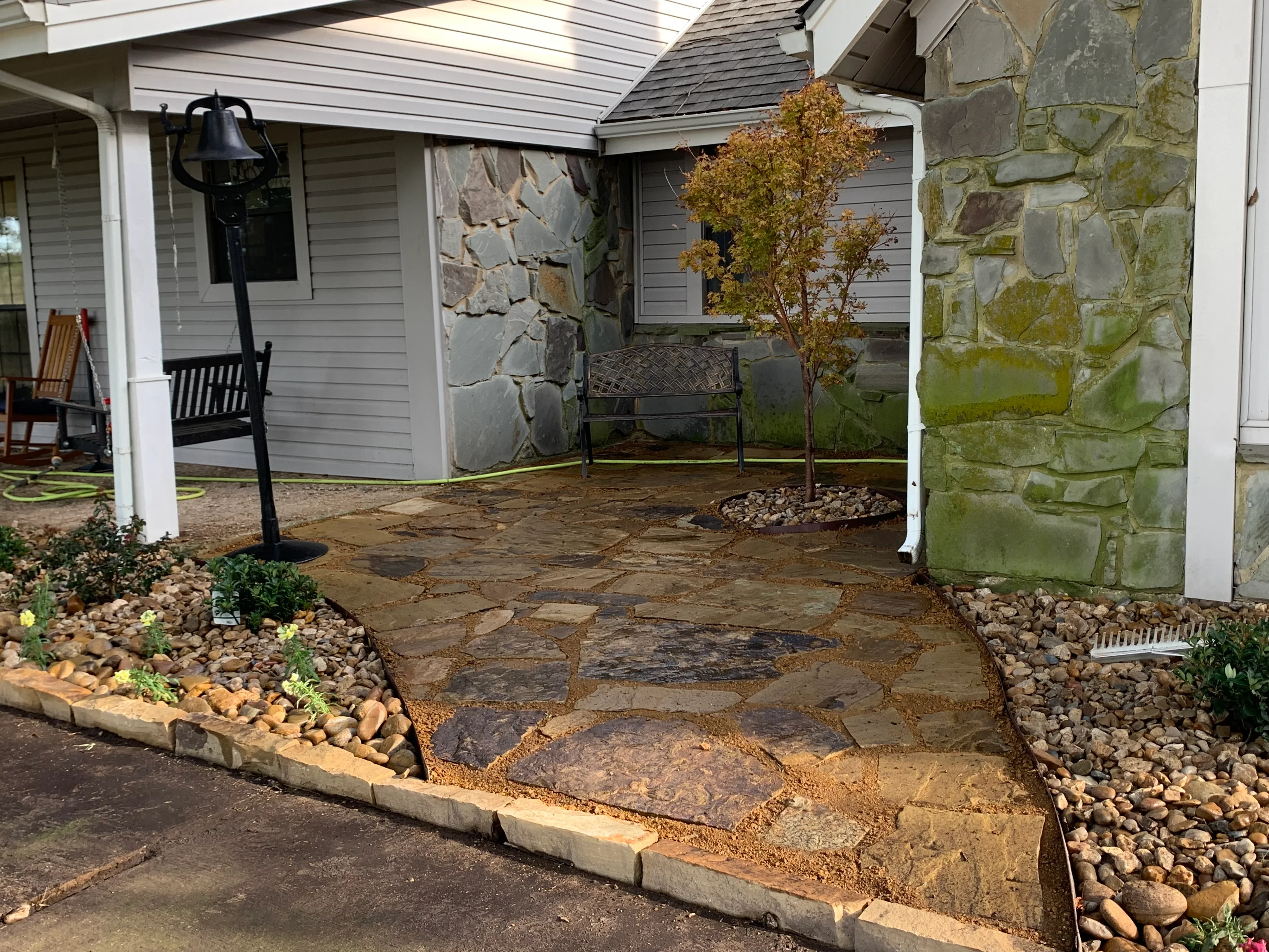 Irregular flagstone patio with concrete edging and river rock planting beds
